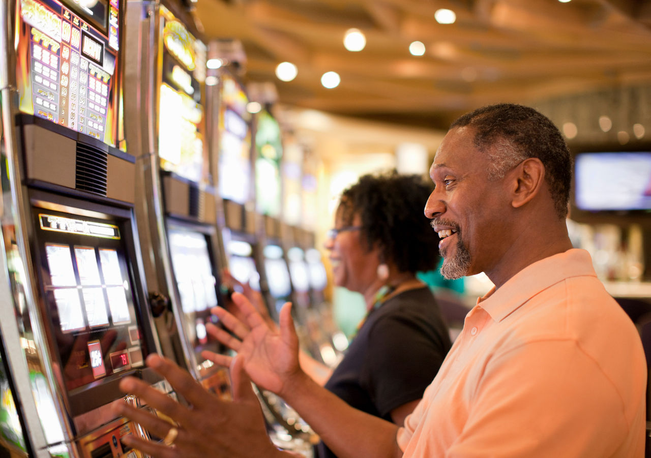 man and woman using slot machines