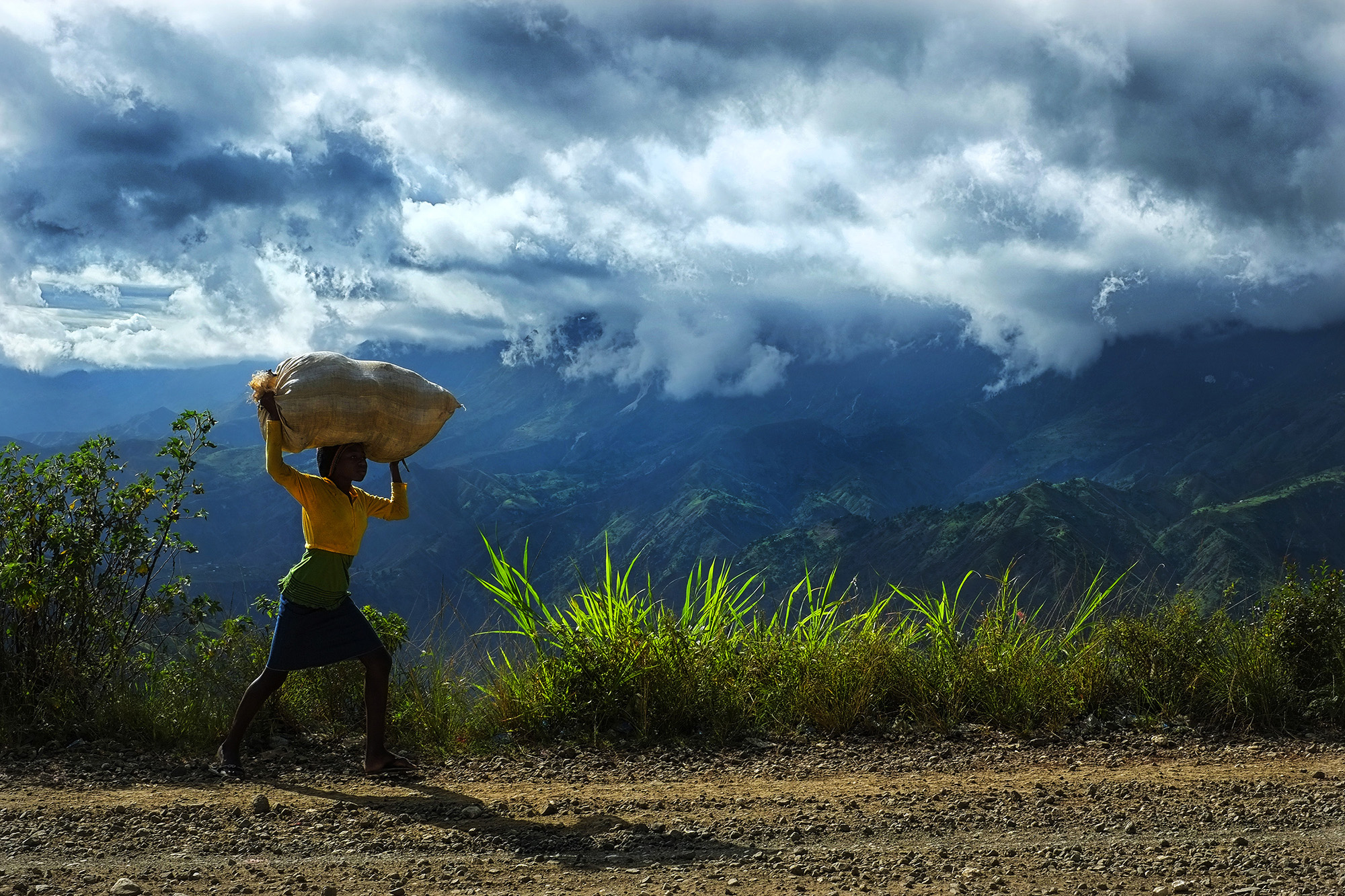 A girl carries a bag of produce to sell in the mountains outside of Port au Prince, Haiti.