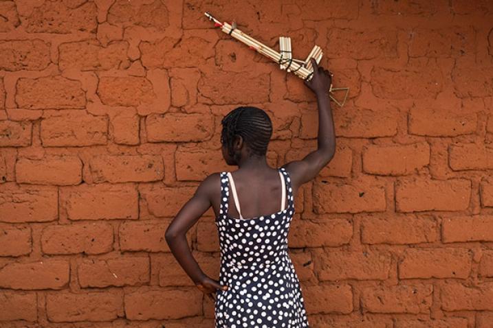 Girl facing a wall holds up a fake gun.