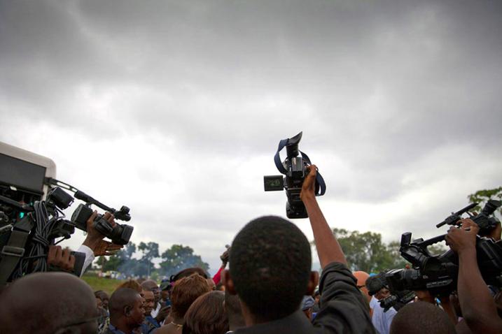 A journalist holds up his video camera above the crowd. 