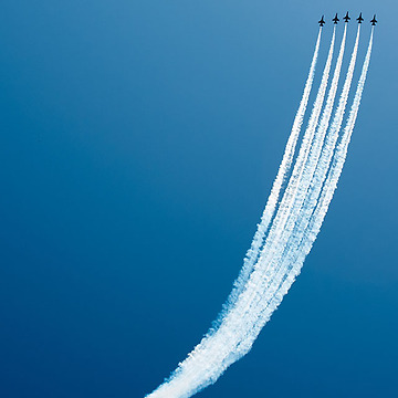 five jets flying upwards in formation against a blue sky