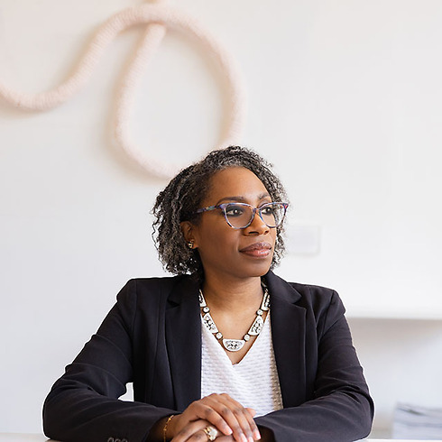 professional Black woman in glasses sitting at a table with folded hands